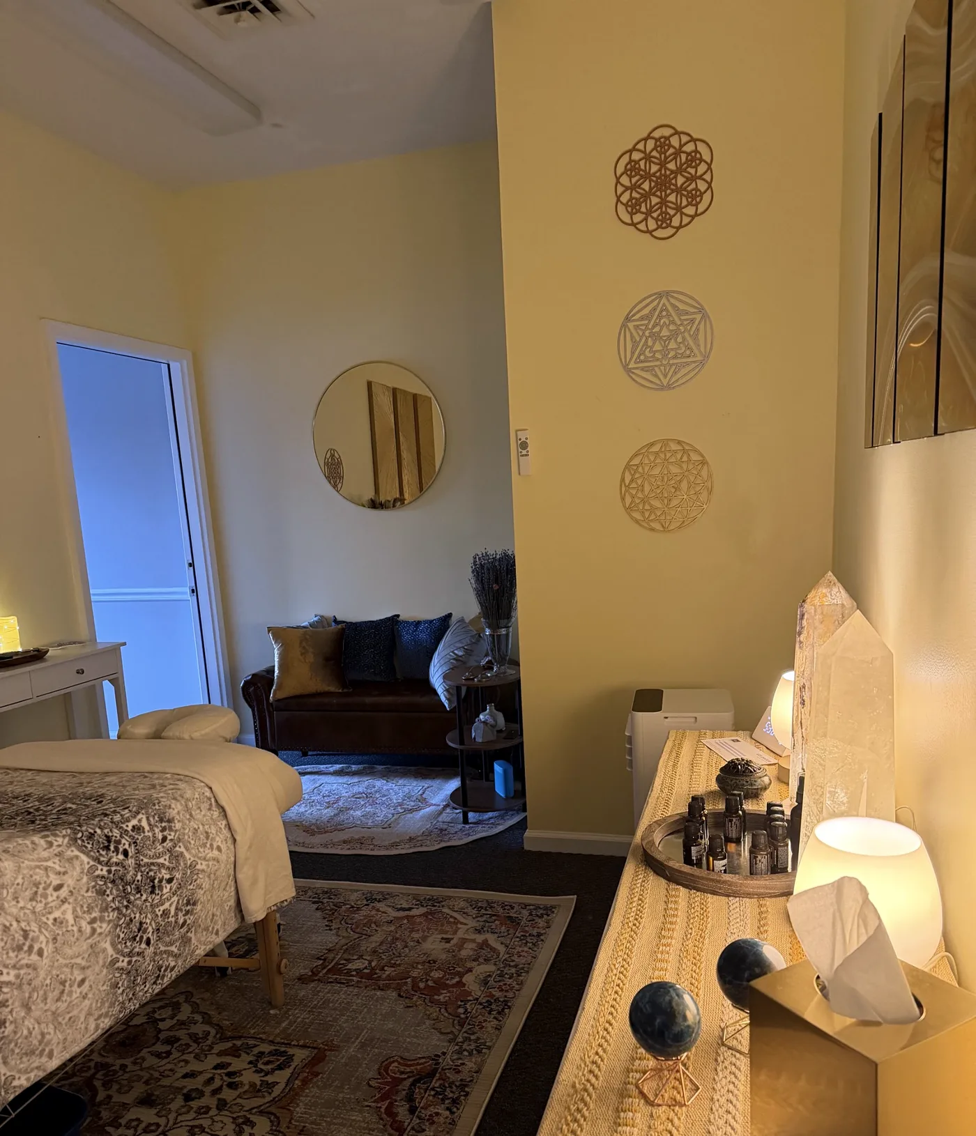 Sacred geometry wall art, the settee, and the credenza with crystals and oils