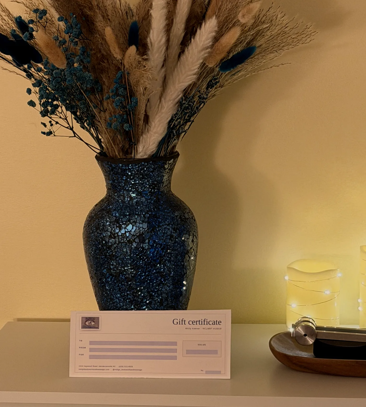 Blue mosaic vase with dried grasses, candles, and an Indigo gift certificate