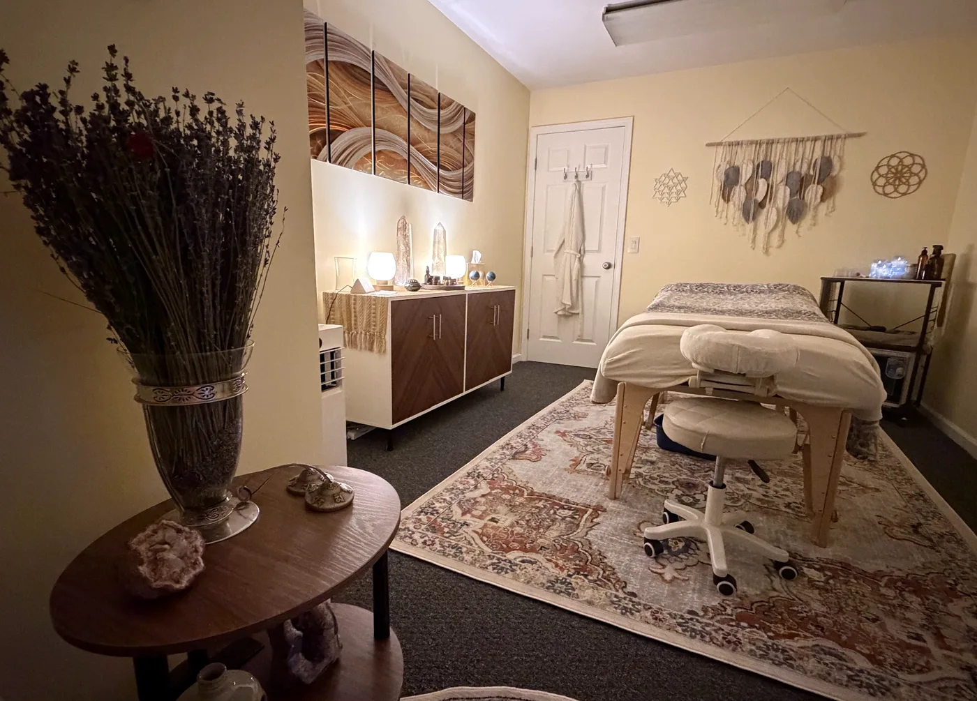 The treatment room: massage table, lit credenza with crystals, and the wave panels on the wall